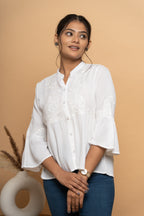 Close-up schiffli embroidery detail on white flared top by Poshida